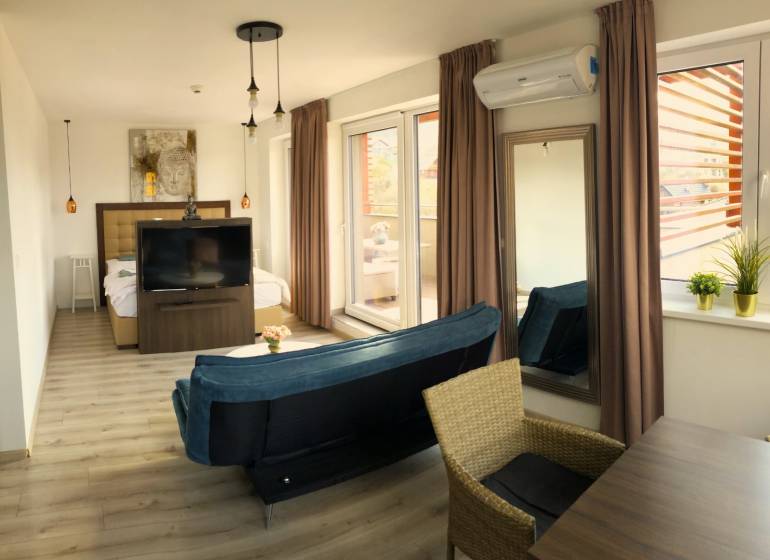 Helle 2-Zimmer-Wohnung mit Holzboden, Sofa und großen Fenstern.