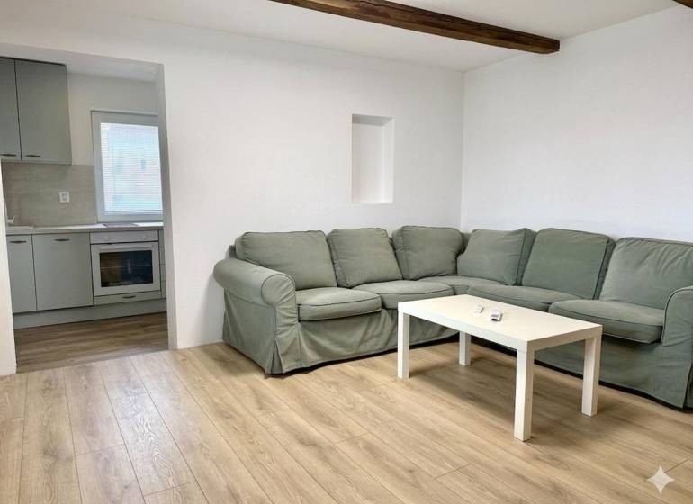 Wohnzimmer mit Ecksofa, Holzboden und Küche in einem Einfamilienhaus.