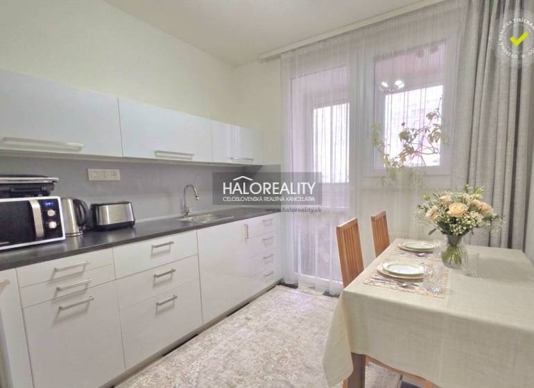 Küche in einer 4-Zimmer-Wohnung mit Tisch, Stühlen und Geräten.