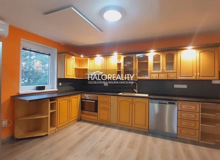 Küche mit orangefarbenen Wänden, Holzschränken und einem Boden mit Holzdekor in einem Einfamilienhaus.