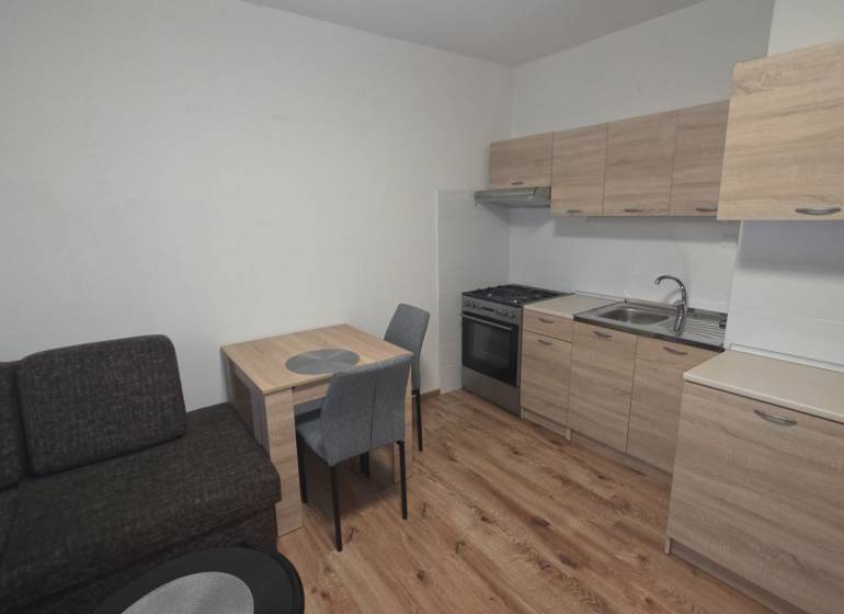 Küche in einer Einzimmerwohnung mit Holzdekor auf dem Boden und Möbeln.