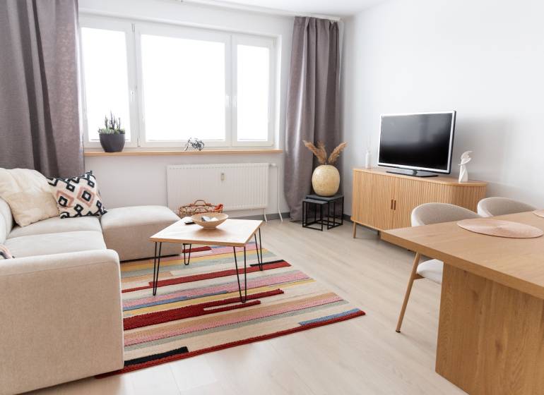 Wohnzimmer in einer 4-Zimmer-Wohnung mit Holzboden, Sofa und Fernseher.