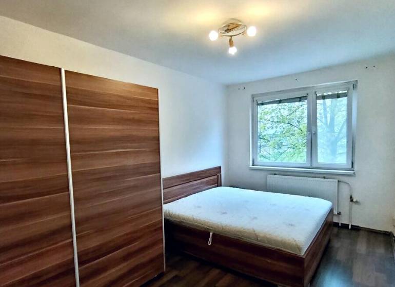 Schlafzimmer mit Schrank, Bett und Boden in Holzoptik in einer 4-Zimmer-Wohnung.