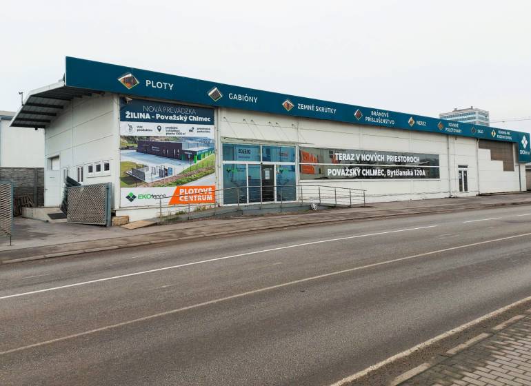 Geschäftsräume in der Kamenna-Straße in Žilina mit Werbeaufschriften und einem leeren Parkplatz.