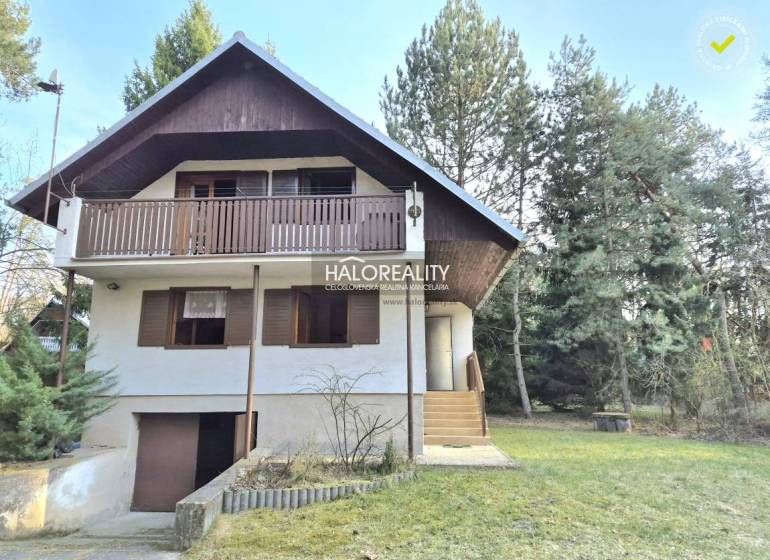 Eine Hütte in Borský Svätý Jur, umgeben von Grün und Bäumen, mit einem Holzbalkon.