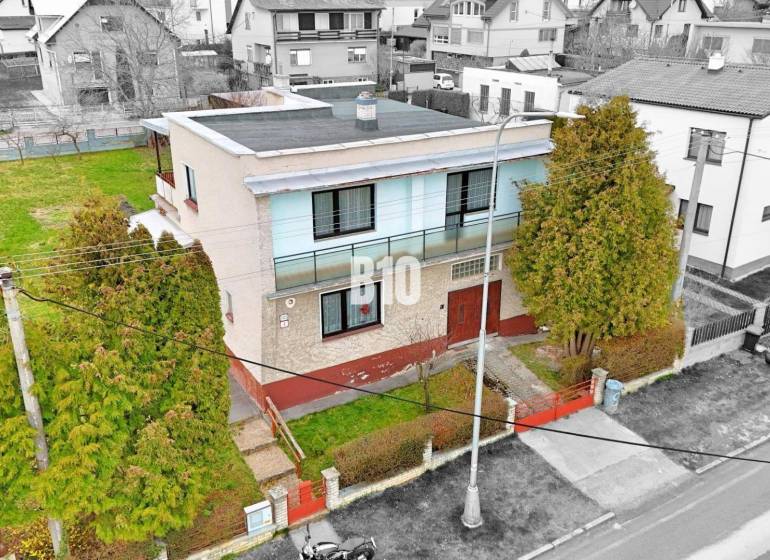 Ein Einfamilienhaus in Martin mit Flachdach, Garten und umliegenden Häusern.