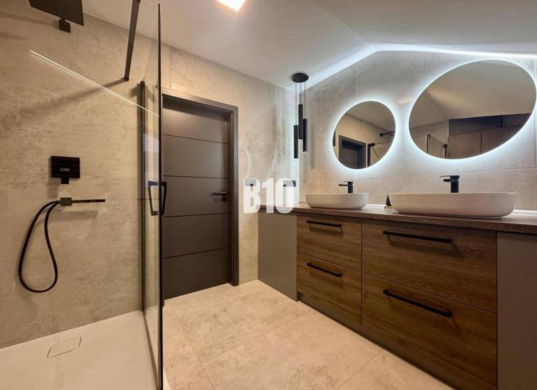 Badezimmer in einer 4-Zimmer-Wohnung mit zwei ovalen Spiegeln und einer Duschkabine.