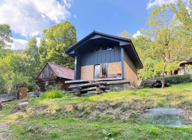 Eine Hütte in Horna Marikova, umgeben von Natur und Holzbauten, an einem sonnigen Tag.
