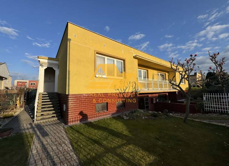 Gelbes Einfamilienhaus in Nové Zámky in einer Straße mit gepflegtem Garten und Gehweg.