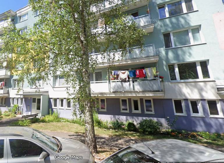 Das Wohnhaus in der Beskydská 9 in Banská Bystrica mit Grünflächen und einer Frau im Vordergrund.