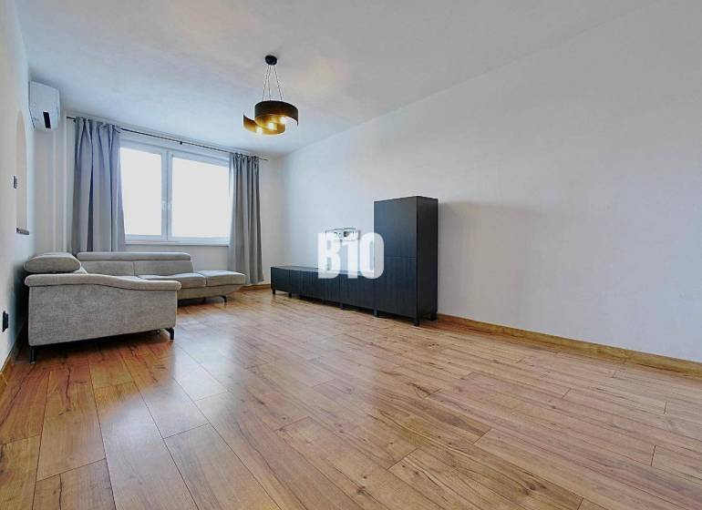 Wohnzimmer in einer 3-Zimmer-Wohnung mit einem bequemen Sofa und einem Boden in Holzoptik.