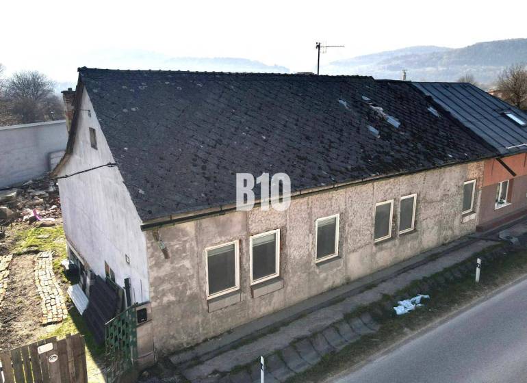 Ein Einfamilienhaus in Bytča mit abgenutztem Dach und Putz, neben der Hauptstraße.