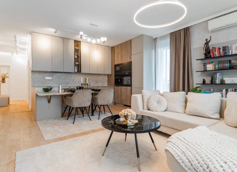 Ein stilvolles Wohnzimmer mit Küche in einer 3-Zimmer-Wohnung, helle Farbtöne, Boden mit Holzdekor.