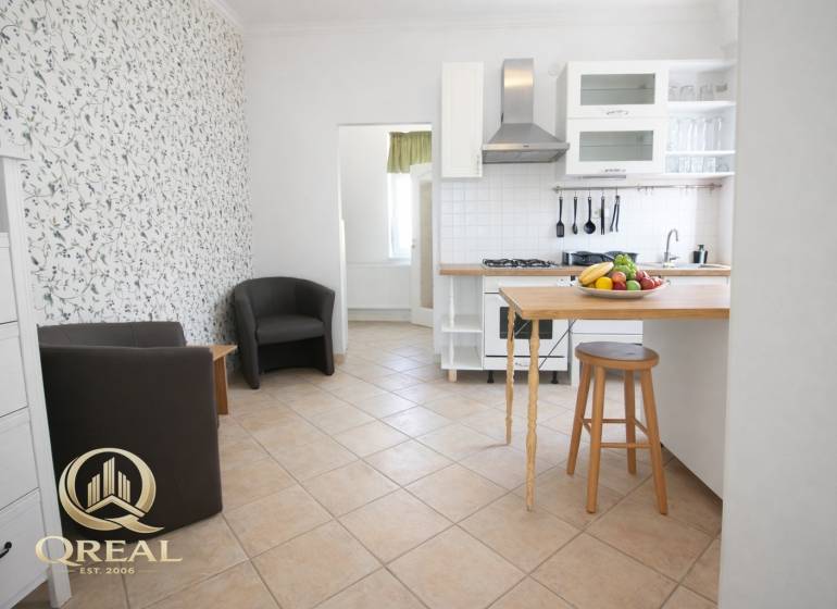 Küche mit Bartresen, Obst und Sesseln in einer Einzimmerwohnung.