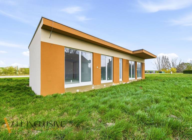 Ein Ferienhaus in Vojka nad Dunajom mit einer Umgebung aus grünem Gras und großen Fenstern.