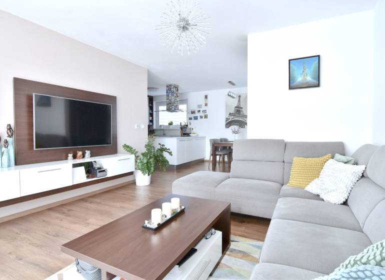 Wohnzimmer in einer 3-Zimmer-Wohnung mit Holzboden und grauem Sofa.