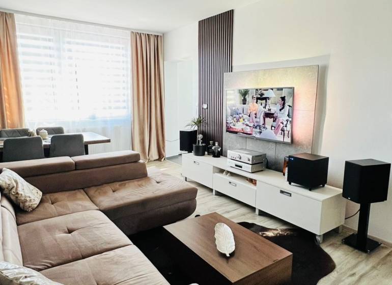 Wohnzimmer mit Ecksofa, TV-Schrank und Boden mit Holzdekor.