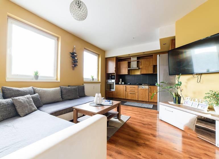 Wohnzimmer in einer 2-Zimmer-Wohnung mit Küchenzeile und Holzboden.