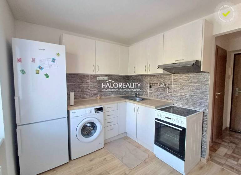 Küche in einer Einzimmerwohnung mit weißen Schränken und Holzboden.