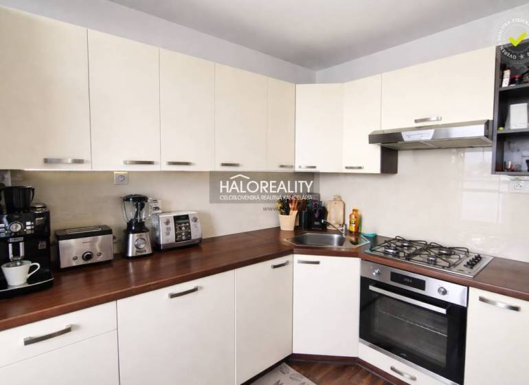 Küche in einer 4-Zimmer-Wohnung mit weißen Schränken und einem Boden in Holzoptik.