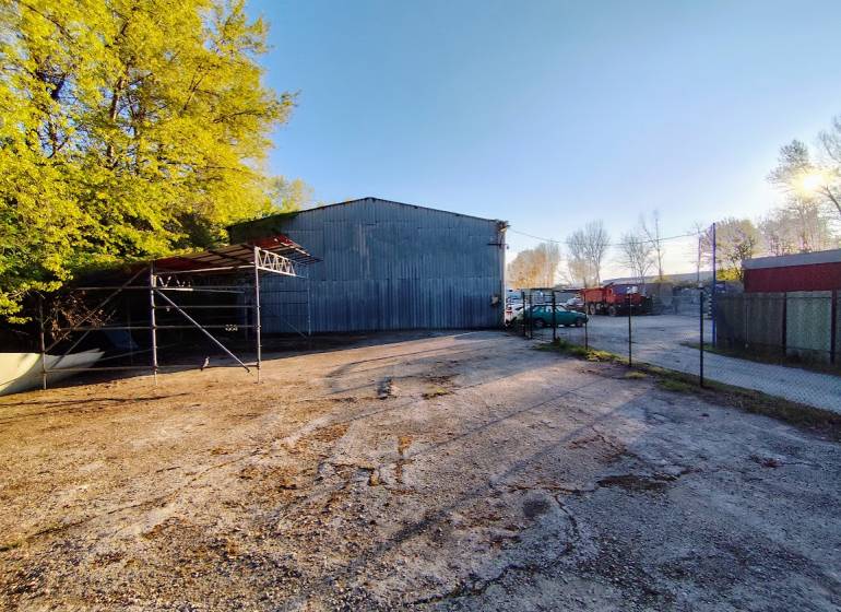 Industrieobjekt mit Parkplatz, umgeben von Bäumen in Nitra, geeignet für kommerzielle Nutzung.