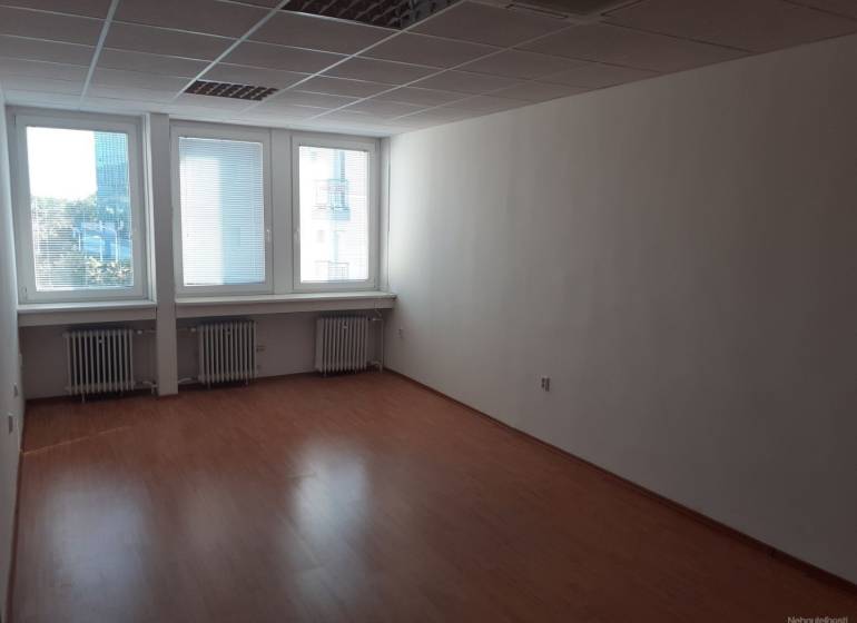 Ein leerer Büroraum mit Holzboden und großen Fenstern.