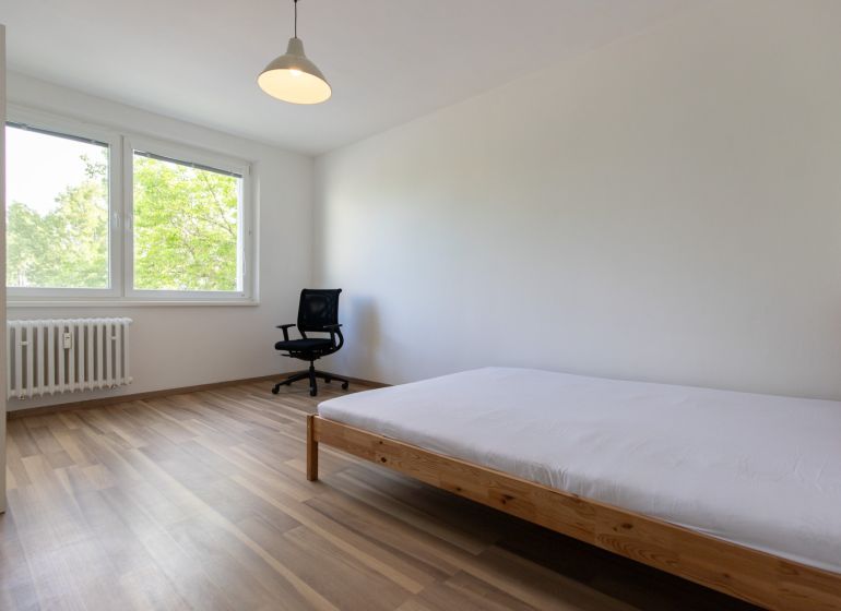 Helles Schlafzimmer in einer 3-Zimmer-Wohnung mit Holzboden und großen Fenstern.