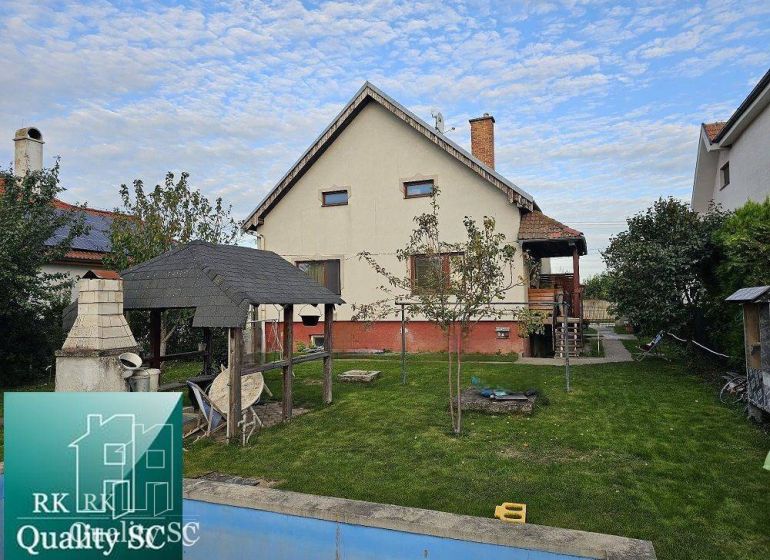 Ein Einfamilienhaus in Turany mit Rasen, Pavillon und einem Außenkamin im Garten.