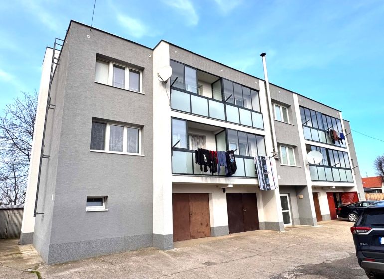 Ein dreistöckiges Wohnhaus mit Balkonen und Autos in Hlboké.