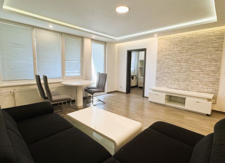 Wohnzimmer einer 4-Zimmer-Wohnung mit Holzboden, Sofa und Essecke.