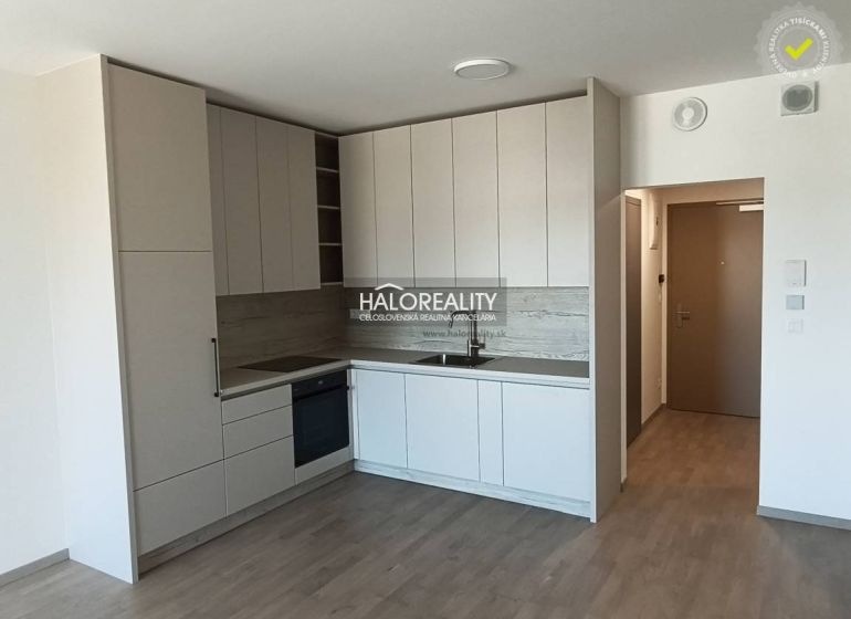 Küche in hellen Farbtönen mit Holzboden in einer Einzimmerwohnung.