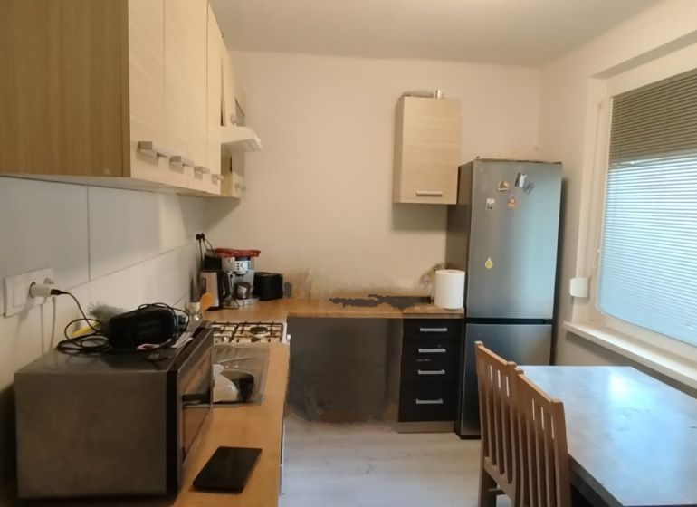 Küche in einer 2-Zimmer-Wohnung mit Geräten, Esstisch und großen Fenstern.