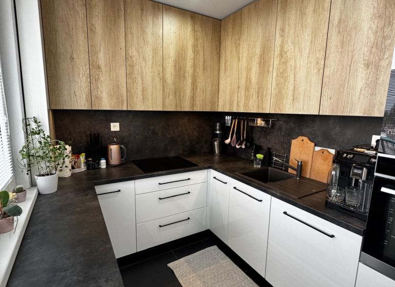 Küche mit weißen Schränken und Holzelementen in einer 3-Zimmer-Wohnung.