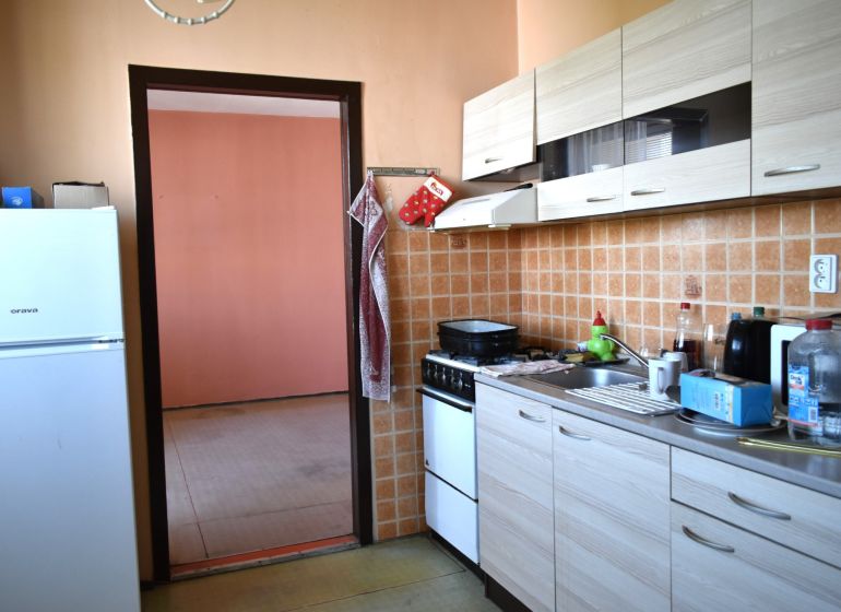 Küche in einer 3-Zimmer-Wohnung mit Fliesenverkleidung und Boden in Holzoptik.