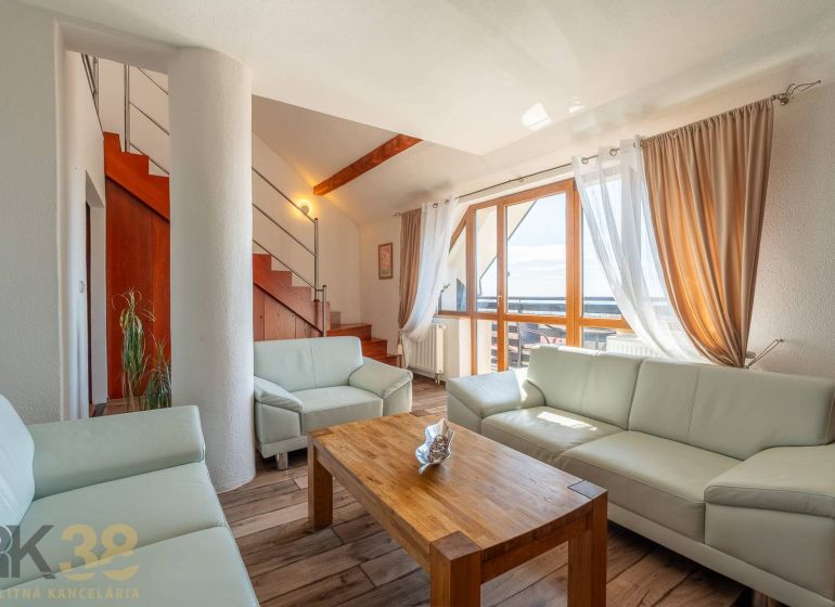Wohnzimmer mit heller Couch, Treppe und Holzboden in einer 4-Zimmer-Wohnung.