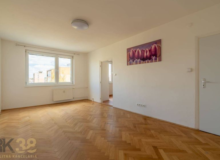 Ein geräumiges Zimmer mit einem großen Fenster, einem Boden in Holzoptik und einem Bild in einer 4-Zimmer-Wohnung.