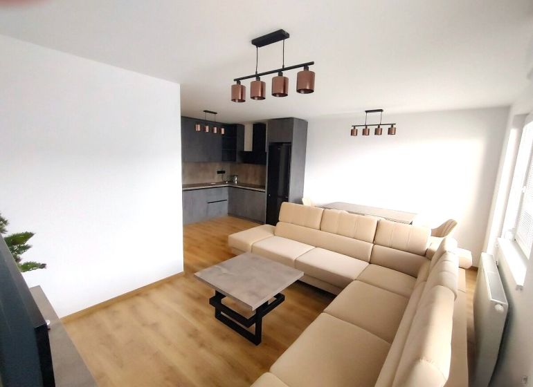 2-Zimmer-Wohnung mit Holzboden, heller Couch und Kochnische.