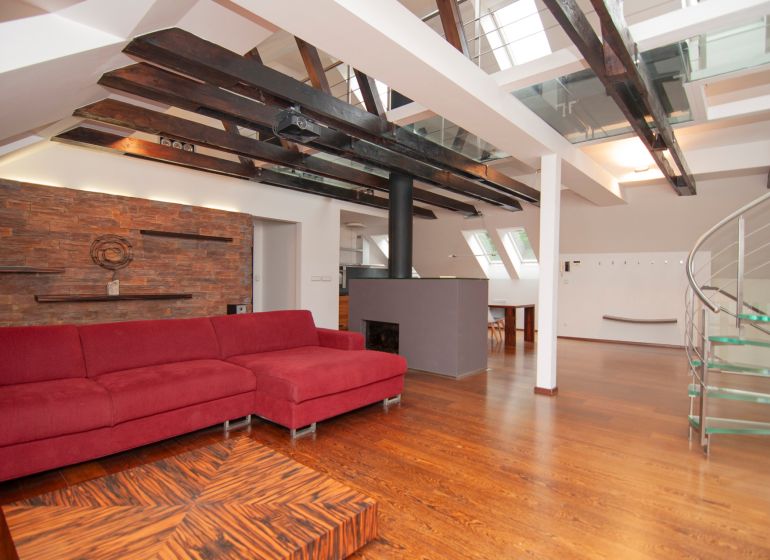 Dachboden-Wohnbereich mit großem rotem Sofa und Holzboden in einer 3-Zimmer-Wohnung.
