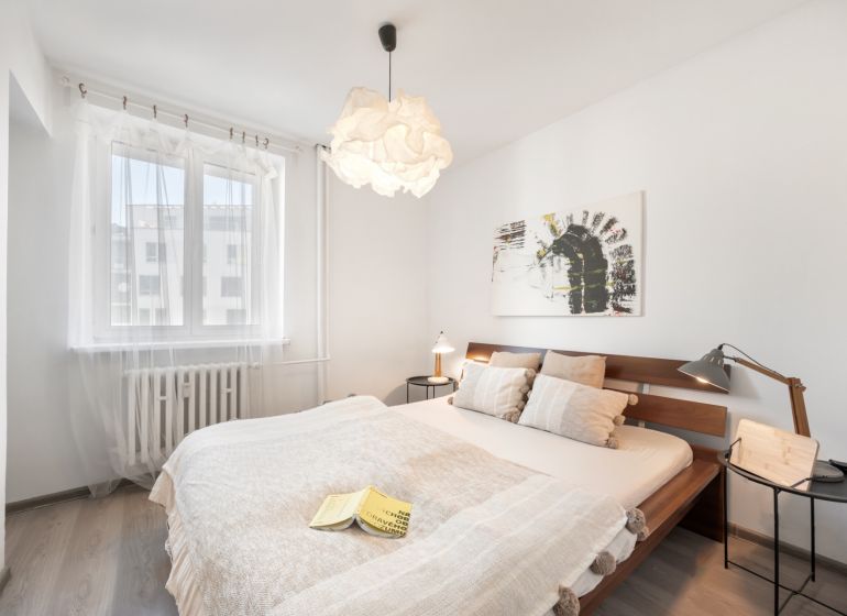 Helles Schlafzimmer mit einem Holzbett, einem Bild an der Wand und einem Boden mit Holzdekor.