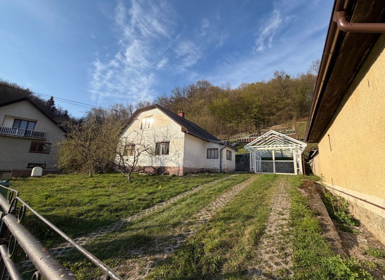 Ein Einfamilienhaus in Štós, umgeben von Grün und einer Holzkonstruktion eines Unterstands.