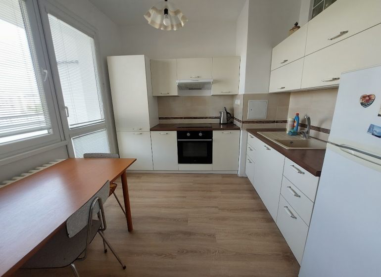 Küche in einer Einzimmerwohnung mit weißen Schränken und einem Holzboden.