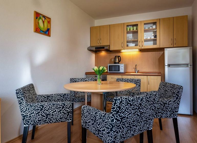 Küchenecke mit Esstisch und Stühlen im Ferienapartment, Boden mit Holzdekor.