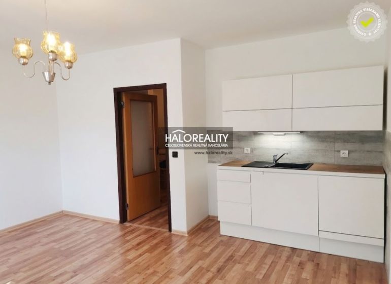 Einzimmerwohnung mit Küche, weißen Schränken und Holzboden, geeignet zur Vermietung.