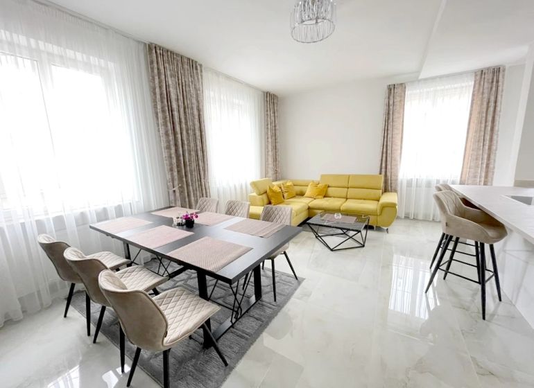 Helles Wohnzimmer mit Esstisch, gelbem Sofa und Barhockern in einer 3-Zimmer-Wohnung.