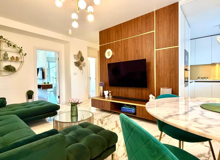 Wohnzimmer in einer 3-Zimmer-Wohnung mit Marmorboden und grünen Sofas.