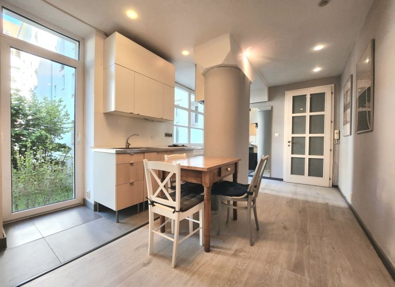 Küche in einer 2-Zimmer-Wohnung mit Holztisch und Boden in Holzoptik.