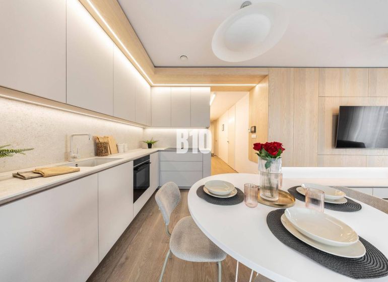 Eine stilvolle Küche in einer 3-Zimmer-Wohnung mit Holzboden und modernen Möbeln.