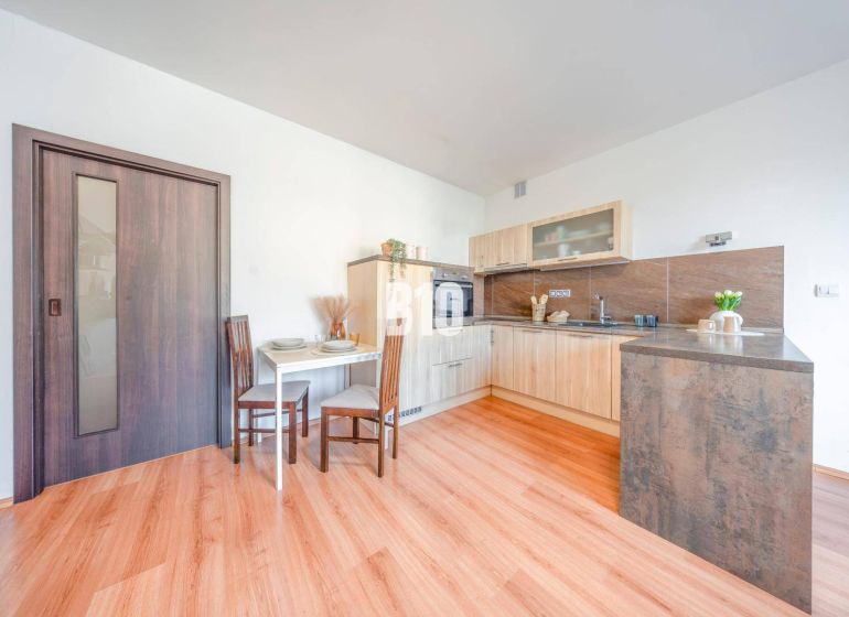 Küchenecke in einer 2-Zimmer-Wohnung mit Holzboden und Esstisch.