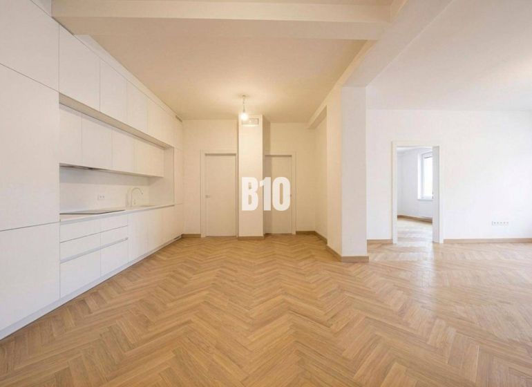 Innenraum einer 3-Zimmer-Wohnung mit weißer Küche und Boden in Holzoptik.