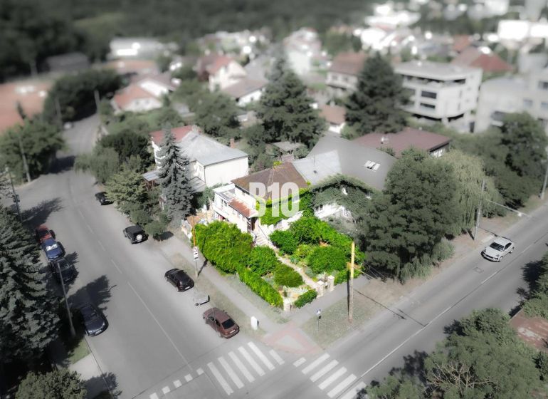 Ein Einfamilienhaus in der Gegend von Bratislava - Altstadt, umgeben von Grünflächen und einer Straße mit Autos.